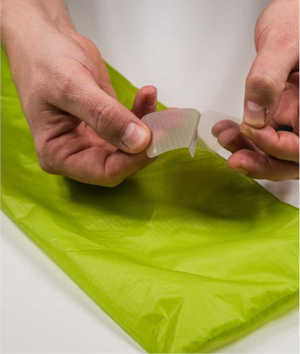 Person peeling a clear plastic sheet over a green surface