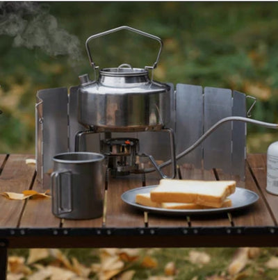 Camping stove with kettle and food on a wooden table outdoors