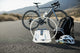 Bicycle, helmet, and water bottle on a road with mountains in the background
