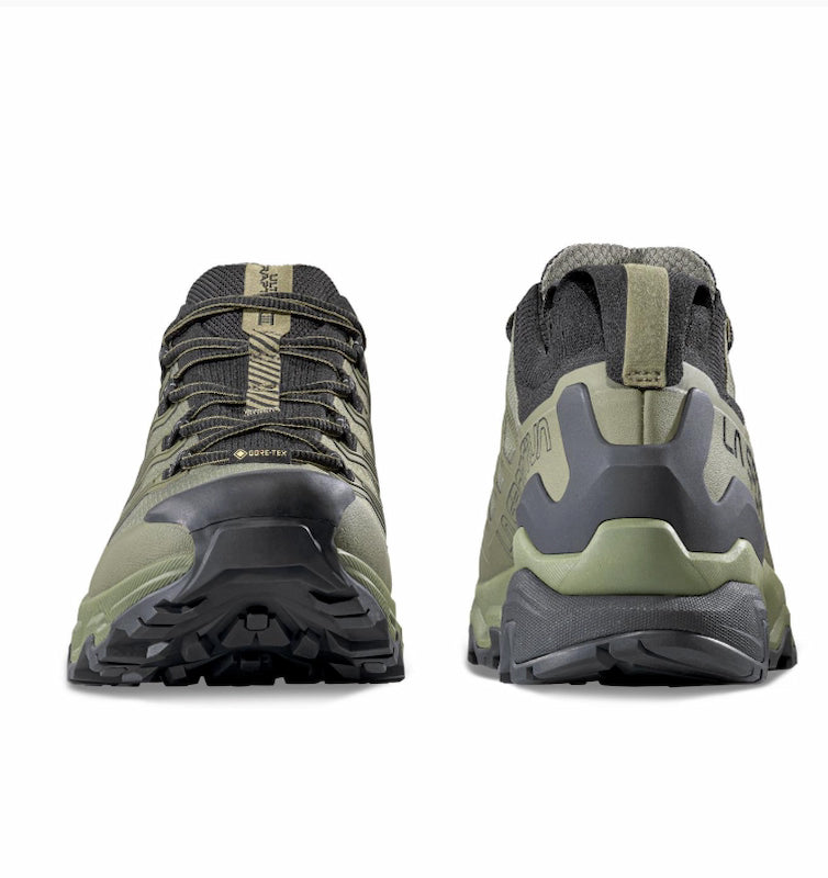 Pair of green hiking shoes with black soles on a white background