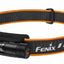 Fenix headlamp with a black and orange adjustable headband, shown on a plain white background.
