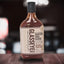 Bottle of Glasseye Creek Bonfire BBQ Sauce on a wooden surface with a blurred background
