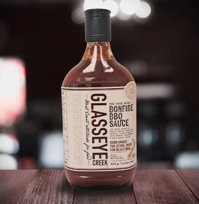 Bottle of Glasseye Creek Bonfire BBQ Sauce on a wooden surface with a blurred background