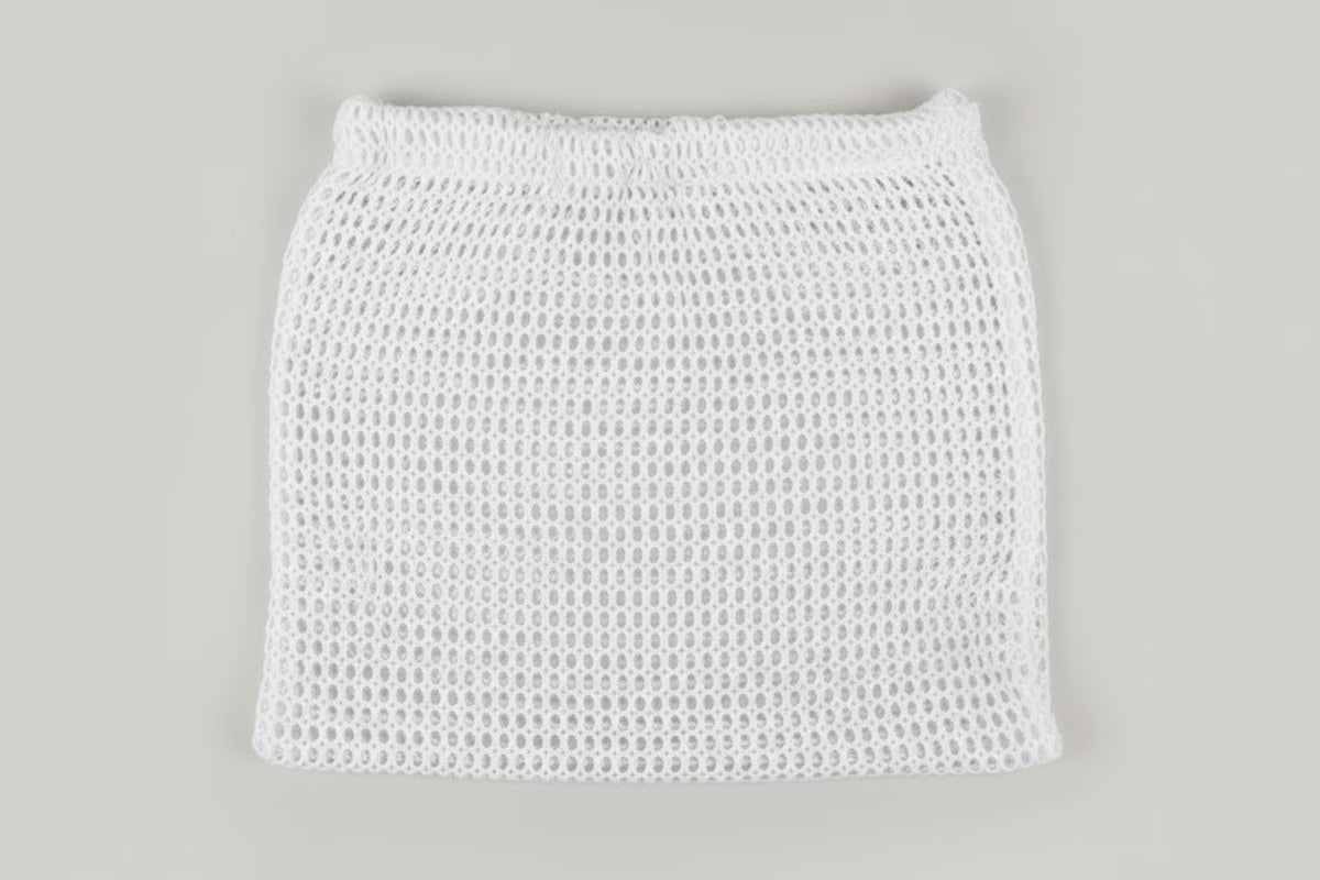 A white open-knit mesh mini skirt with an elastic waistband, shown flat against a solid light gray background.