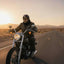 Person riding a motorcycle on a desert road at sunset