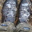 Pair of worn boots with visible wear and snow on a grassy background