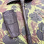 Metal folding shovel with black sheath on camouflage-patterned surface