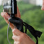 Hand holding a camera with a grip and strap against a blurred green background