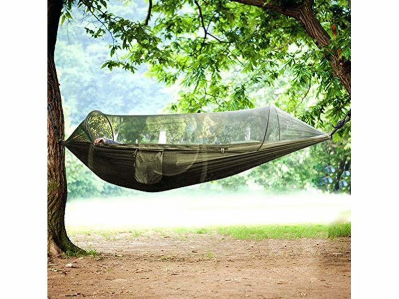 Green hammock with mosquito net hanging between two trees in a forest setting