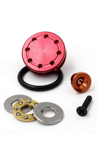 An image of an aluminium piston head for airsoft guns, displayed alongside its components such as seals and a washer. The piston head has a red metallic finish.